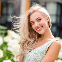 Ukrainische Frau mit blondem Haar lächelt im Sommergarten, authentische Ausstrahlung und natürliche Eleganz